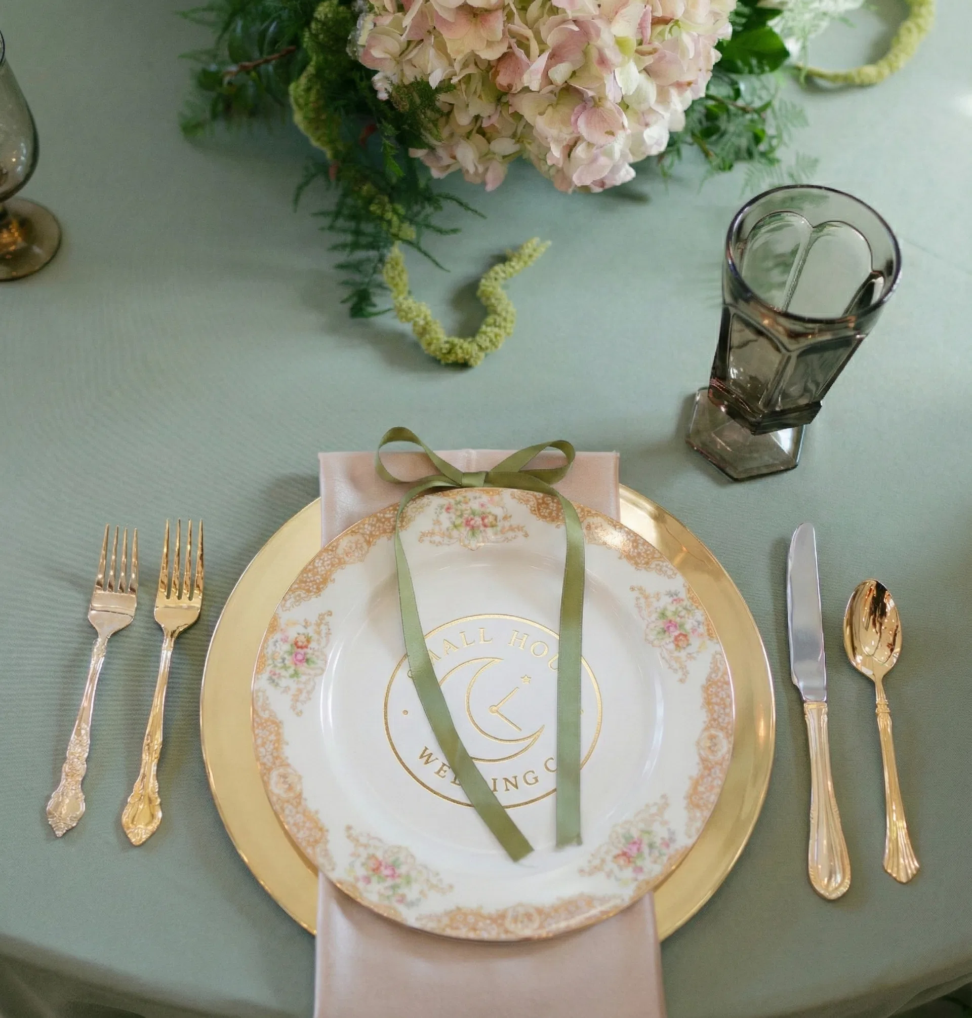 Small Hour Wedding Co logo on vintage china place setting with gold flatware and hydrangea florals